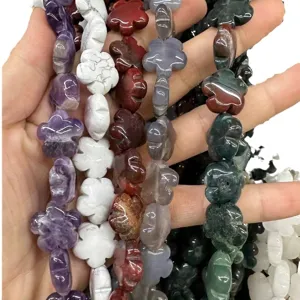 Hand holding various colorful natural stone flower shaped beads for DIY crafts