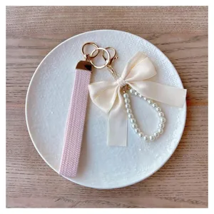 Women pearl keychain wristlet lanyard with cute bow and pink woven strap for keys and bags.