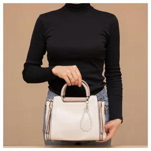 Detail view of a stylish pearl wristband keychain attached to a chic handbag, perfect use.