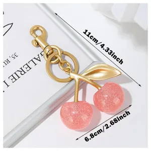 Glitter pink cherry keychain detail shot showcasing sparkly resin fruits and golden metal clasp.