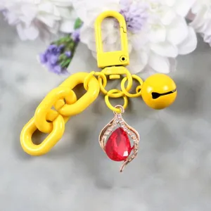 Primer plano detallado de un llavero amarillo brillante con colgante de cristal rojo en gota.