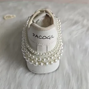 Back view detail of white sneaker decorated with multi-layer elegant faux pearl strings.