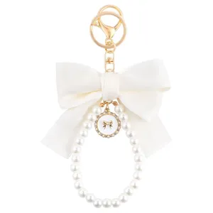 Lindo llavero de perlas blancas con lazo y detalles dorados para bolsos y accesorios de moda.