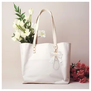 Elegante bolso tote blanco con lindo lazo y colgante de llavero de perlas para uso diario.