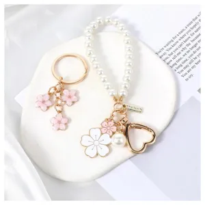 Close-up of cute pearl wrist keychain and pink cherry blossom metal key rings set detail.