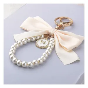 Elegante portachiavi di perle con fiocco in tessuto e chiusura dorata, perfetto per borse e chiavi.