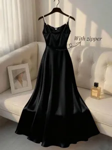 Detail view of the elegant black satin camisole dress featuring delicate pearl straps.