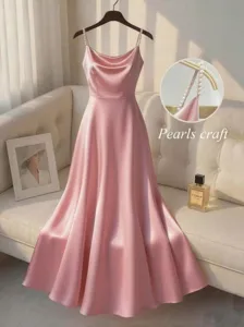 Detail view of pink satin slip dress with pearl beaded straps, elegant event apparel close-up.