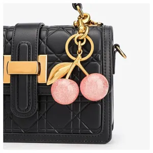 Nahaufnahme eines niedlichen glitzernden rosa Kirsch-Taschenanhängers mit goldenem Stiel.