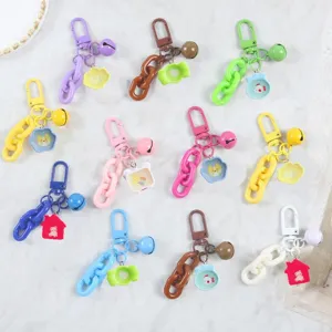 Close up view of colorful keychain charms, resin cartoon pendants, metal clasps and bells.