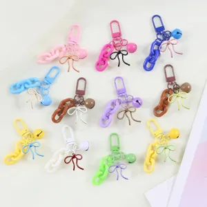 Gros plan détaillé de porte-clés en alliage aux couleurs bonbon avec jolis nœuds et cloches.