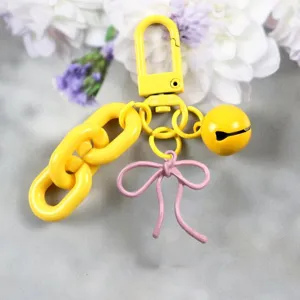 Vue détaillée du porte-clés en alliage de couleur bonbon avec un nœud rose et une cloche.