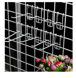 Vue détaillée des crochets de grille en métal blanc, crochets muraux pour supermarché.