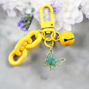 Llavero de aleación amarillo brillante con mariposa azul translúcida y un cascabel.