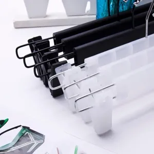 Gros plan détaillé de cintres de pantalon noirs et translucides multifonctions avec pinces.