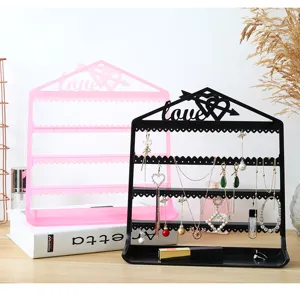 Close-up detail of plastic house-shaped jewelry organizer stand with multi-tier earring display.