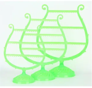 Dettaglio espositore per gioielli verde a forma di arpa, supporto multistrato per orecchini.