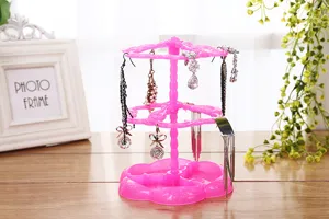 Espositore per gioielli rotante in plastica rosa a due livelli per appendere orecchini da scrivania.