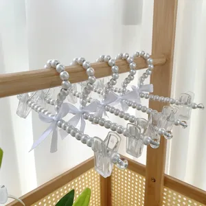 Parel kledinghangers met clips en witte strikken, elegante parel hangers voor broeken en kleding.