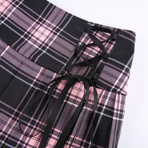 Detailed view of a pink and black plaid pleated skirt featuring stylish black ribbon lace-up side.