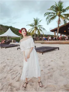 Detailed view of the white off-shoulder beach dress, featuring delicate hollow embroidery.