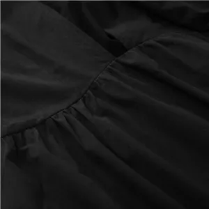 Close-up detail of black womens dress featuring pleated gathered texture and v-neck style.