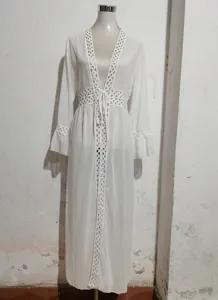 Detailed view of this white beach cover-up with delicate hollow-out lace trim and long sleeves.