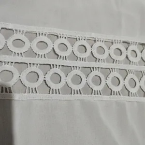 Detailed close-up view of white round-hole lace trim, highlighting exquisite texture.