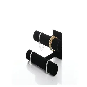 Detail view of a two-tier black velvet jewelry display stand for holding bracelets and watches.