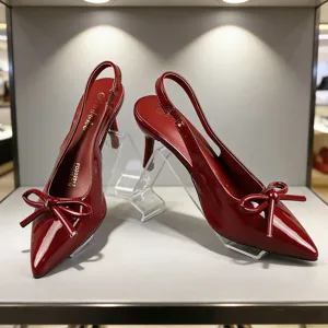 Rode lakleren puntneus slingback hakken met strik getoond in elegante vitrine.