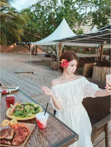 Detail shot of a white off-shoulder bohemian beach dress, perfect for summer seaside resort wear.