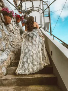 Vista dettagliata del lungo cardigan da spiaggia in pizzo con bordi ondulati eleganti.