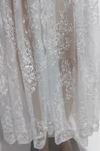 Dettaglio abito lungo copricostume mare pizzo bianco, elegante motivo floreale donna.