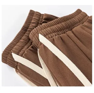 Detailed close-up of brown casual trousers featuring elastic waistband and side stripe trim.