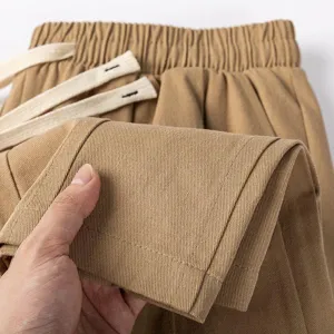 Close-up detail of men's casual pants showing soft cotton fabric texture and pleats.