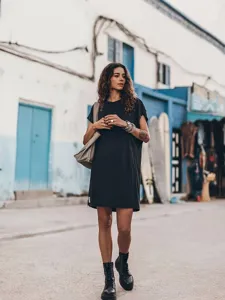 Detail shot of the black short sleeve casual dress shown in outdoor street lifestyle scene.