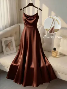 Closeup of elegant brown satin dress with pearl beaded straps, detail shot in luxury room setting.