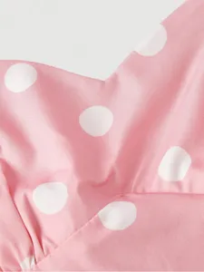 Close-up detail of pink polka dot fabric showing soft texture and classic patterned design.