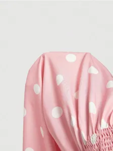 Close-up detail of women pink polka dot fabric with elastic smocked texture design element.