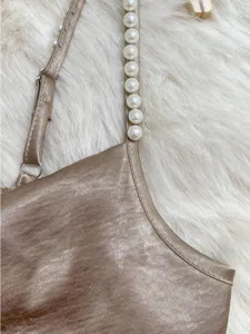 Close-up of elegant golden satin dress strap featuring handmade white pearls for a luxury look.