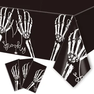 Detail view of black Halloween tablecloth and matching napkins featuring white skeleton hands.