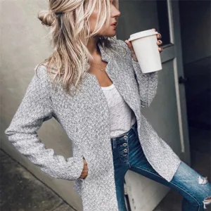 Detailed shot of a stylish grey herringbone tweed jacket worn by a model in street style.