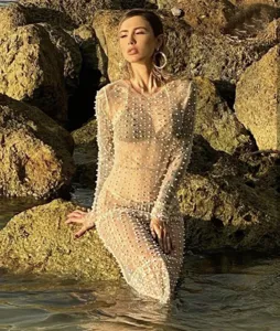 Detalle en primer plano del vestido largo de malla transparente con perlas y pedrería brillante.