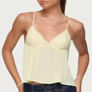 Vista detallada de una camiseta de tirantes amarillo pálido con encaje fino y dulce lazo.