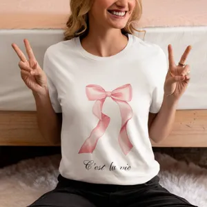 Dettaglio in primo piano della t-shirt bianca da donna con fiocco rosa e testo francese.