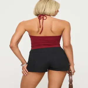 Women summer solid color backless halter crop top with black shorts detail view.
