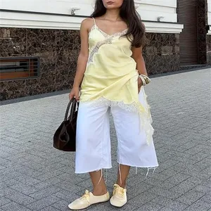 Detailed shot of trendy women lace camisole paired with white wide leg trousers outdoors.