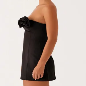 Close-up detail of the elegant black strapless mini dress featuring a striking 3D fabric rose.