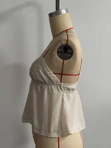 Detailed view of white beaded camisole, stylish V-neck sleeveless tank top with embellishments.