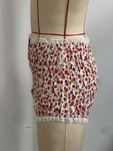 Vista ravvicinata degli shorts arricciati con stampa di fragole rosse e delicato pizzo bianco.